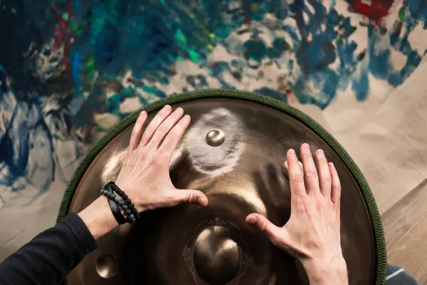 A musicians hand playing the handpan with other people. Handpan is a term for a group of musical instruments that are classified as a subset of the steelpan.