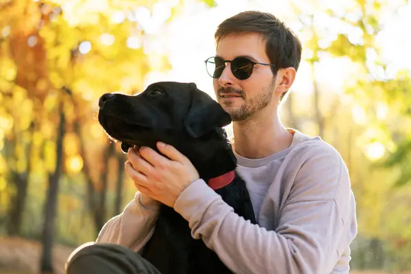 Een Man Met Een Zonnebril Knuffelt Zijn Hond Het Herfstpark Stockfoto
