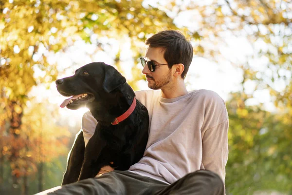 Tipul Ochelari Soare Își Îmbrățișează Câinele Parcul Toamnă Apus Imagine de stoc