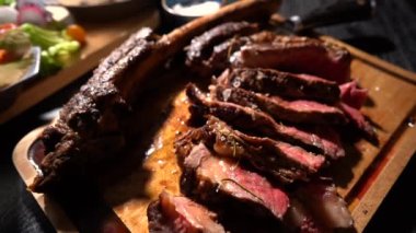 Kesme tahtasındaki büyük bir mutfak bıçağıyla bifteği kesme işlemi. Sulu sığır eti parçalara ayrılmış.. 