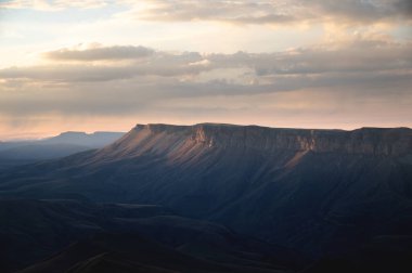Beautiful autumn mountain landscape in the setting sun. Rocky cliff in the clouds.