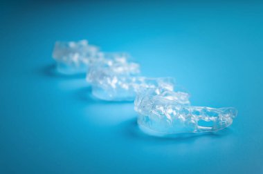 Invisible aligners on a blue background with copy space. Plastic braces for teeth alignment.