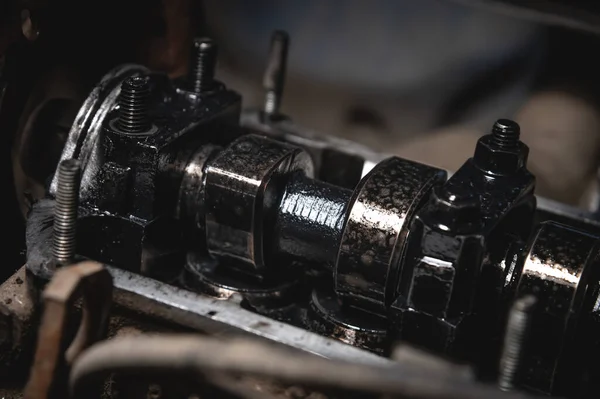 Close-up of a dirty cylinder head camshaft on a broken old engine in shallow depth of field.