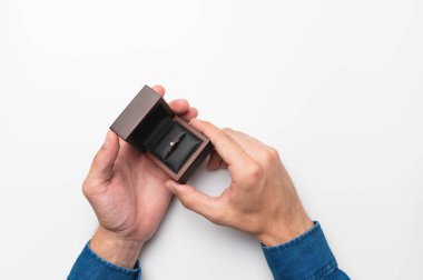 a mans hand holds a diamond engagement ring in a wooden elegant box, making a marriage proposal.