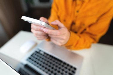 Female students hands with a phone on the background of a modern laptop and desktop. Freenacer working from home, hipster profession.