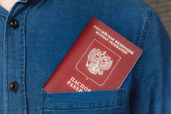 Passport in the pocket of a denim shirt, close-up. Travel abroad concept.