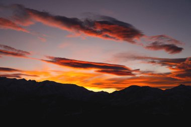 Mountains in the clouds at sunset in summer. Aerial view of the mountain peaks in the fog. Beautiful landscape with high cliffs. Sunset cloud landscape for background.