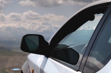 SUV concept with mountains in the clouds. Close-up of the nose of the car.