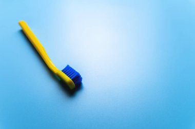 Mavi arka planda parlak renkli bir diş fırçası var. Reklamcılığın için bir yer. Diş sağlığı kliniği afişi