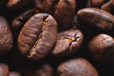 Close up extreme macro group of roasted brown or black coffee beans background in shallow depth of field. Enchanting coffee aroma.
