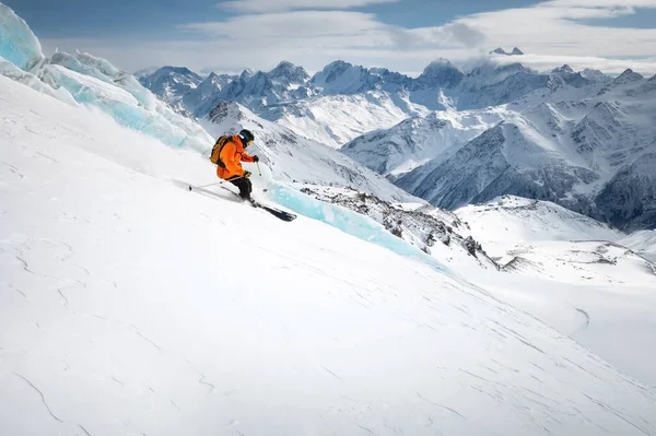 一个滑雪者正在高山上的阳光灿烂的一天滑下山坡 下坡时 在高山上的冰川旁边自由驰骋 — 图库照片