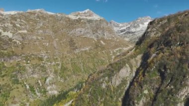 Dağlarda sonbahar. Yeşil orman, büyük kayalar ve karlı dağlar. Dağ geçidi. Yüksekten çekiyoruz, İHA.