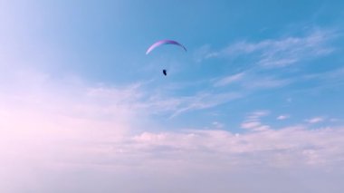 Güneşli bir günde mavi gökyüzüne doğru uçan bir gemi yolculuğundaki paraglider pilotu. hava görünümü.