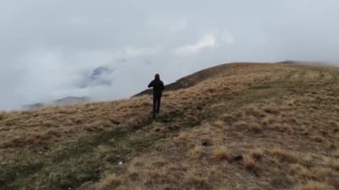 Sisli ve bulutlu bir havada bir uçurumun kenarında yürüyen bir adamın havadan görünüşü..
