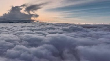 Ufuktaki karla kaplı dağ zirvesi yeri ve gökyüzünü kaplayan kabarık beyaz bulutlar denizi ile insansız hava aracının hava fotoğraflarıyla kaplı..