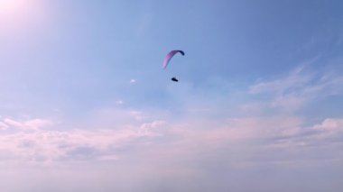 Kanatlı ve Kokan 'lı bir paraşütçü, güneşli bir havada mavi gökyüzüne karşı bir gemi yolculuğu yapıyor. Hava sporları. Boş zaman.