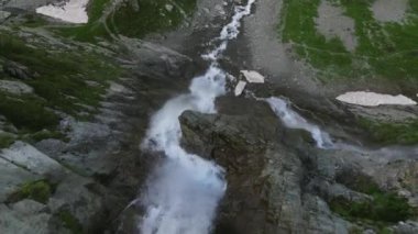 Bir şelalenin tepeden tırnağa destansı akışı. Dağın yamaçlarında şelale var. Güçlü bir su akıntısı volkanik kayalardan aşağı akar. Kafkas ya da Avrupa Alp Dağları.