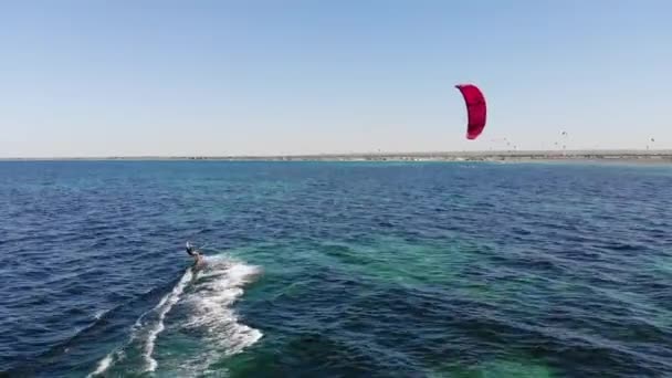 海岸からのカイトサーファーの空中ビュー セーリング ウォータースポーツ中に高速で女性カイトサーファー切断波のドローン映像 — ストック動画