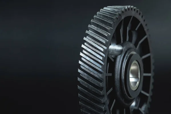 Black timing gear of an internal combustion engine on a black background.