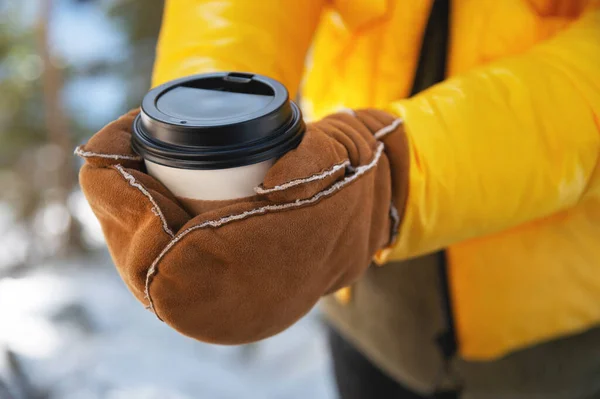 手袋をしている女性は 屋外の公園で冬の街でコーヒーの紙コップを持っています 冬のコンセプトで熱くて暖かい飲み物 手を閉じて — ストック写真