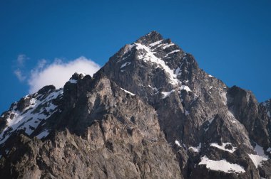 Himalaya tepelerinin manzarası. Güneşli bir günde, tenha bir dağın tepesinde karla kaplanmış..