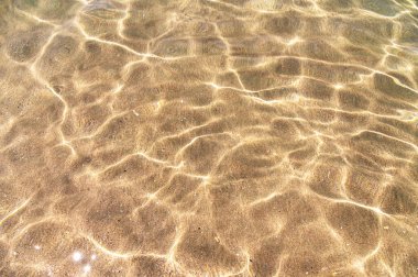 Şeffaf berrak deniz, yakın plan. Geçmişi. Deniz kumlu tabanı. Suyun üzerindeki en üst manzara.