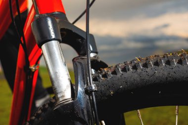 Kapalı bisiklet ön süspansiyon çatalı off-road bisiklet lastiği açık hava bulutları ve dağlara karşı.