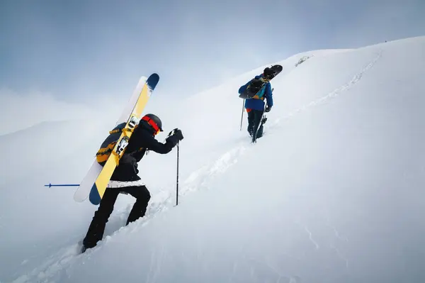 Backcountry climbers walking with skis in the mountains. Ski tourism in alpine landscape with snowy mountains. Adventure winter sport.