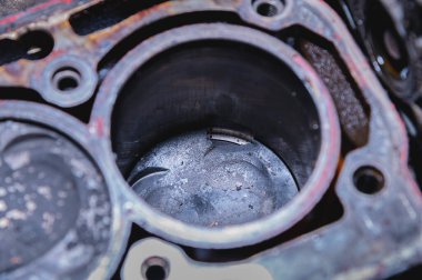 Hasarlı bir içten yanmalı motorun yakın çekimi. Parçalanmış motorda, is ve dokuma parçalı pistonlar kurulur. Kırık pistonlar. Araç motorunun uygunsuz çalışması.
