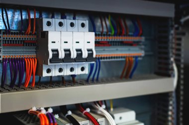 Çeviriciler ve kontrol kablolarıyla çevrili bir üretim hattındaki elektrik kontrol kabininde bir sürü anahtar var. seçici odak.