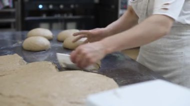 Fırın işçilerinin kadın elleri ekmek yapmak için terazinin üzerinde tartılmak üzere hamurun parçalarını ayırıyor. Fırın işi. Lezzetli ve sağlıklı ekmek üretimi.
