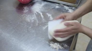 Dişi eller bir somun ekmeği hamur şeklinde yoğurur ve pişirme kabına koyar..