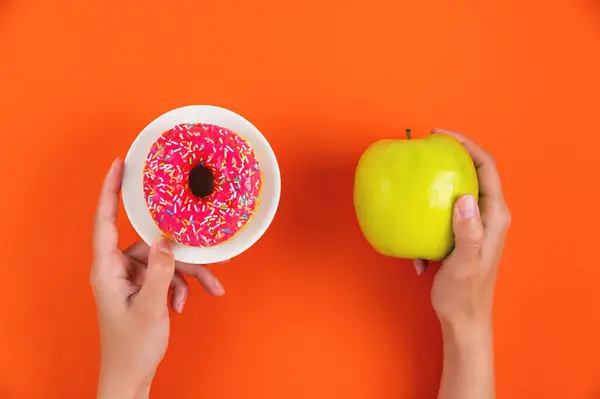 Kezek Egy Almát Egy Fánkot Mutatnak Mint Egészséges Életmód Koncepciót Jogdíjmentes Stock Fotók