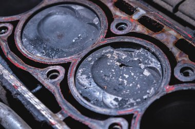 Hasarlı bir içten yanmalı motorun yakın çekimi. Parçalanmış motorda, is ve dokuma parçalı pistonlar kurulur. Kırık pistonlar. Araç motorunun uygunsuz çalışması.