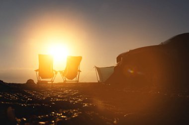 Arabalı bir turist kampı. Arka planda sabah güneşleri, açık hava dinlenme alanı..