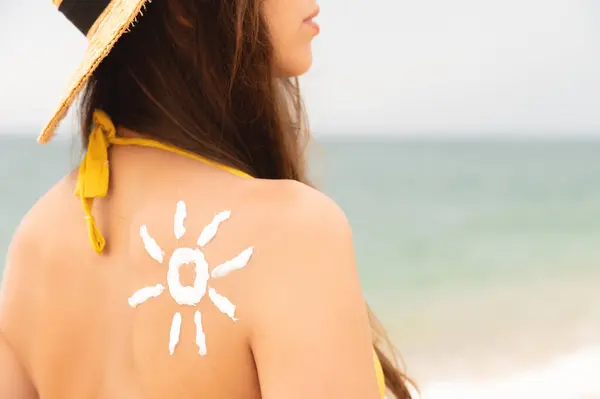 happy girl with the sun on her back by the sea in nature. drawing with cream in the shape of a sun on the back, skin care. Sun protection. Suntan cream.