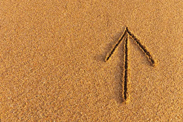 Drawn arrow on the sand. drawing of an arrow sign pointing up, path direction.