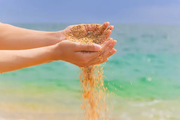 Young woman with sand in her hands. Yellow sand crumbles into and through a womans hands.