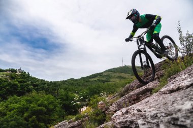 Spor. Bisikletçi gökyüzüne karşı. Genç bir adam dağ bisikleti sürüyor. Doğası gereği. Yokuş aşağı, MTB. Sıra dışı spor.