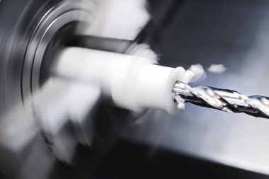 Textolite, polietilen ya da propilenden yapılmış bir eser üzerinde CNC torna operasyonu. Üretim üssünün otomasyonu. Çipler uçuyor.
