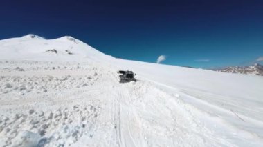 Kar aracının hava görüntüsü. Yüksek dağlık bir kar yamacında aşırı serbest dolaşım için iz bırakan çalışan bir kar aracı. FPV bir kayak merkezinde kar temizleme aracı etrafında uçuyor..