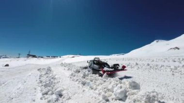 Modern kızıl kar tımarcısı dağların tepesinde at sürüyor. Güneşli bir günde kayak pisti hazırlamak, Kafkasya.