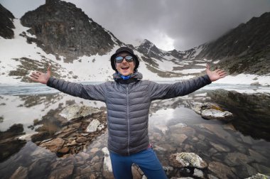 Dağ gölünün yanında duran mutlu adam. Vahşi doğa konsepti, turistik yerleri keşfetmek, yürüyüş....