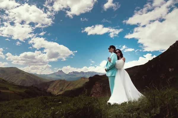 Young wedding couple together in the mountains. Bride hugs groom, newlyweds in the mountains, panoramic view.