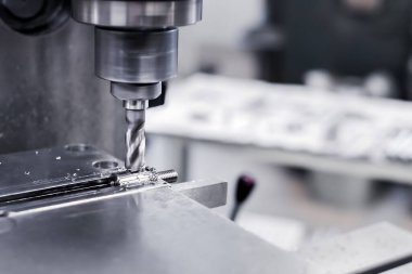 Üretimde, bir matkap alüminyum çelik plakayı matkapla deliyor. Metal bir matkap endüstriyel bir makinede çelik işyerinde delikler açar. Metal endüstrisi. Yakın plan..