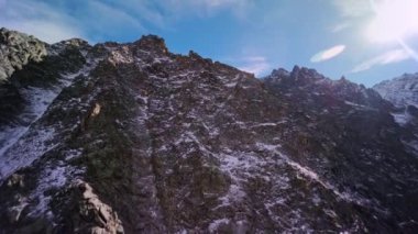 Hava manzarası, dağın tepesine tırmanmak, yüksek tepeden atlamaya hazırlanmak, Alp güneşli manzarası. Birinci şahıs görüşlü spor dronu, destansı kaya manzarası