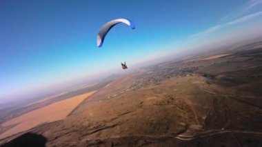 Bir FPV insansız hava aracının hava görüntüsü. Bir paraglider atleti küçük bir dağın yamaçlarına yakın uçar. Sonbaharda FPV insansız hava aracından kırsal alanlarda ücretsiz paraşüt uçuşu.