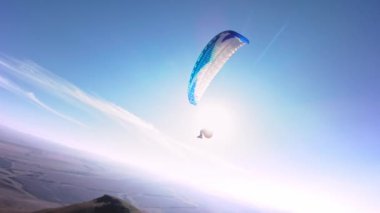 Bir FPV insansız hava aracının hava görüntüsü. Bir paraglider atleti küçük bir dağın yamaçlarına yakın uçar. Sonbaharda FPV insansız hava aracından kırsal alanlarda ücretsiz paraşüt uçuşu.