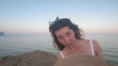 Beyaz elbiseli, beyaz elbiseli, genç, beyaz tenli bir kadın, sıcaktan kaçmak için şapkasıyla birlikte. Çok sıcak..