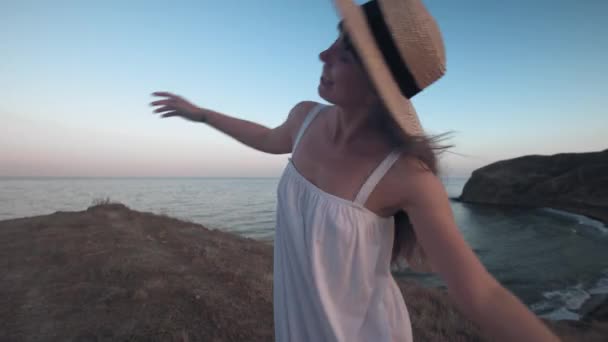 Γελώντας Όμορφη Γυναίκα Γυρίζει Φορώντας Ένα Ψάθινο Καπέλο Στην Ακτή — Αρχείο Βίντεο